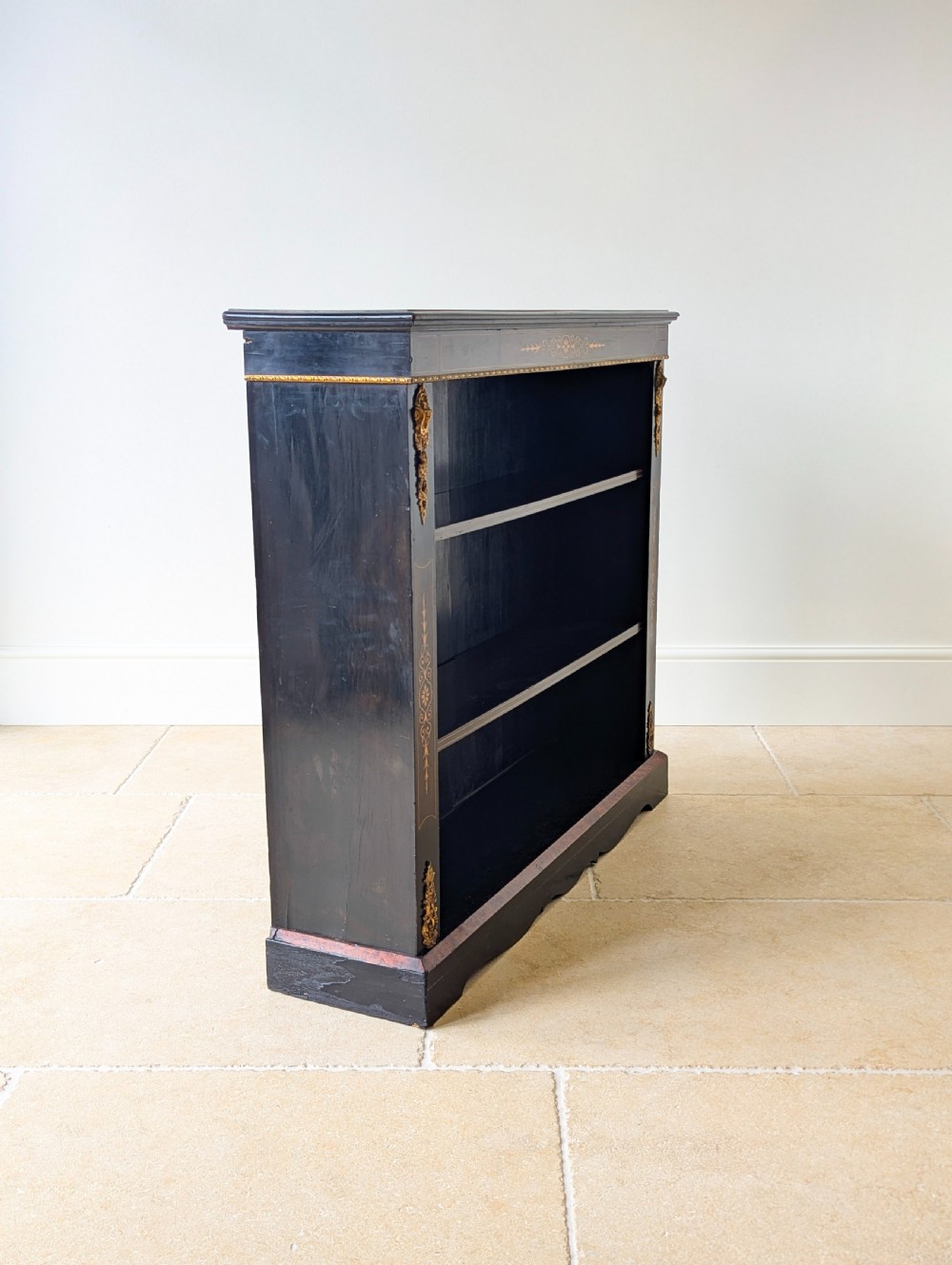 A Victorian ebonised open bookcase with three shelves, gold inlay, and gilt bronze mounts along the side uprights. View X