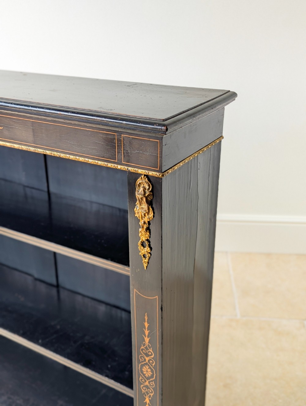 A Victorian ebonised open bookcase with three shelves, gold inlay, and gilt bronze mounts along the side uprights. View XIII