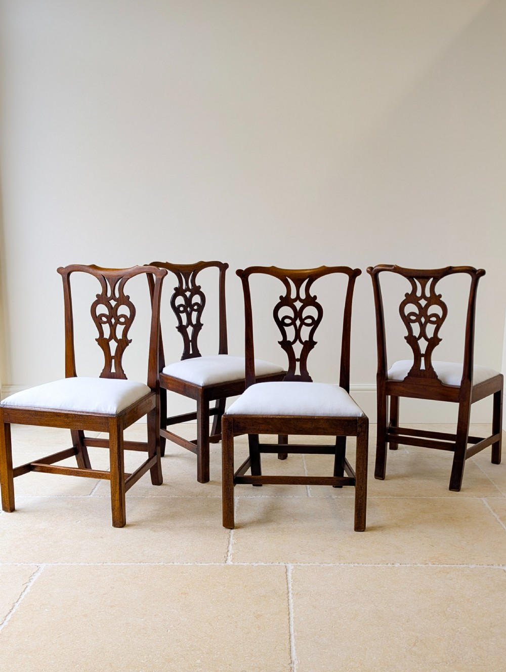 A set of four antique Georgian Chippendale mahogany dining chairs with pierced splat backs, drop-in white fabric seats, and H-stretcher bases. View III
