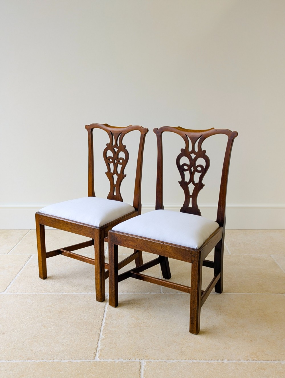 A set of four antique Georgian Chippendale mahogany dining chairs with pierced splat backs, drop-in white fabric seats, and H-stretcher bases. View VIII