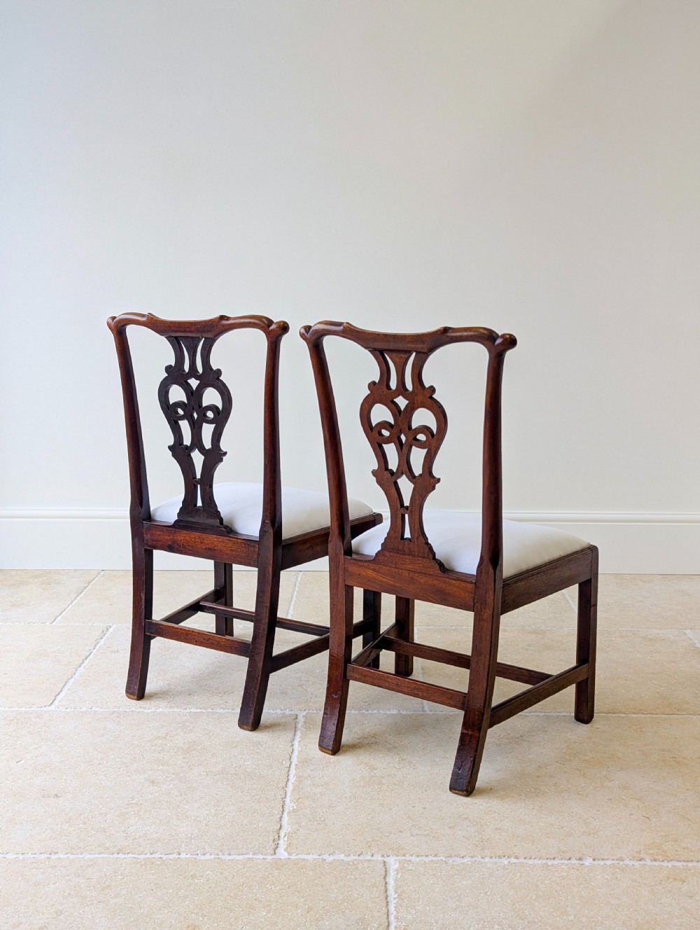 A set of four antique Georgian Chippendale mahogany dining chairs with pierced splat backs, drop-in white fabric seats, and H-stretcher bases. View XI