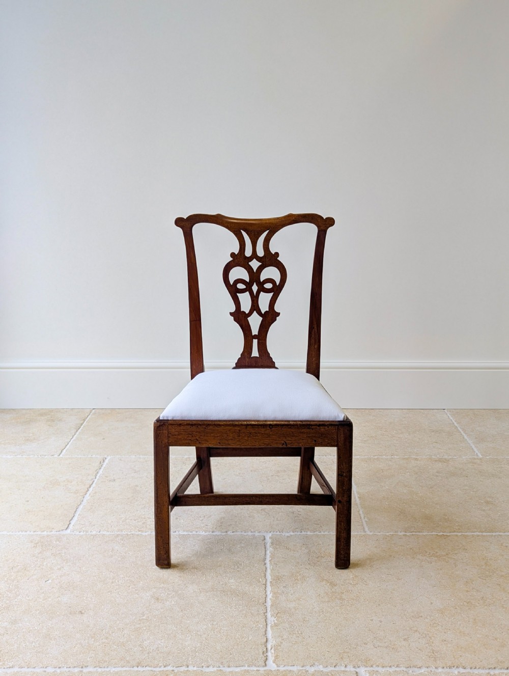 A set of four antique Georgian Chippendale mahogany dining chairs with pierced splat backs, drop-in white fabric seats, and H-stretcher bases. View XIV