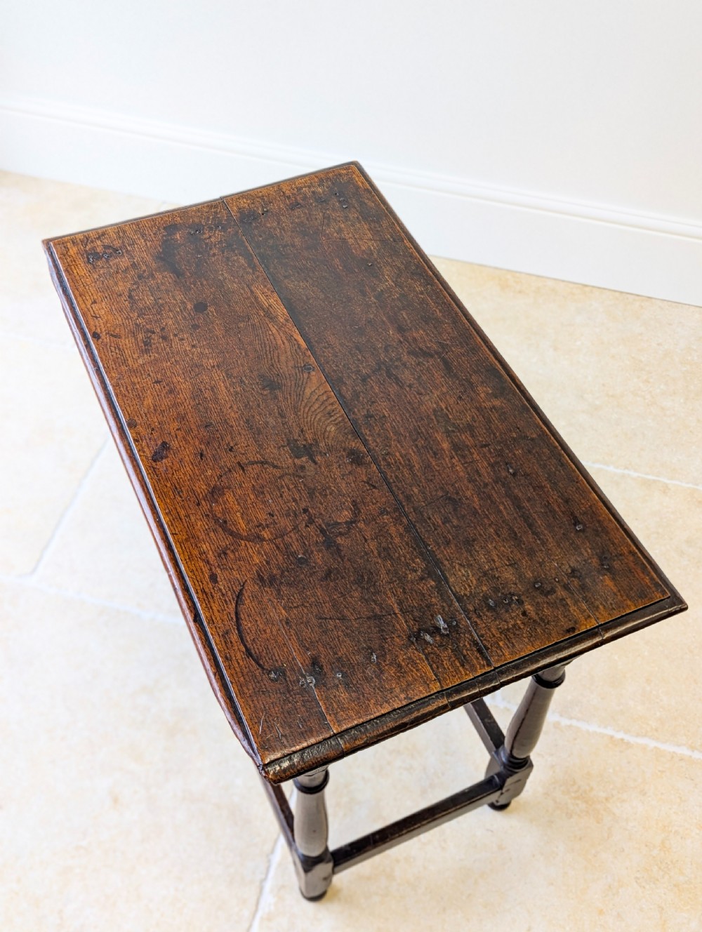 A late 17th-century dark oak side table with turned legs, lower stretchers, and a single drawer featuring brass drop handles. View III