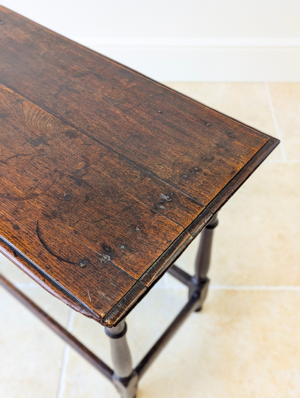 A late 17th-century dark oak side table with turned legs, lower stretchers, and a single drawer featuring brass drop handles. View V