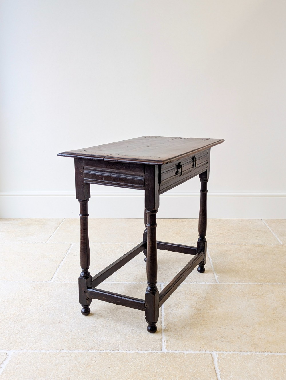 A late 17th-century dark oak side table with turned legs, lower stretchers, and a single drawer featuring brass drop handles. View VI