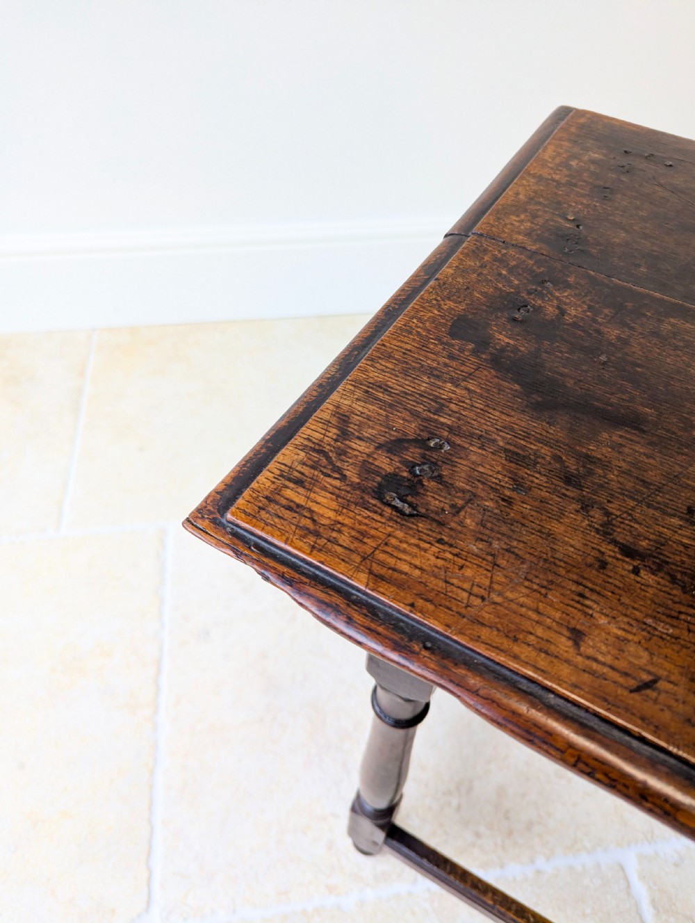 A late 17th-century dark oak side table with turned legs, lower stretchers, and a single drawer featuring brass drop handles. View VII