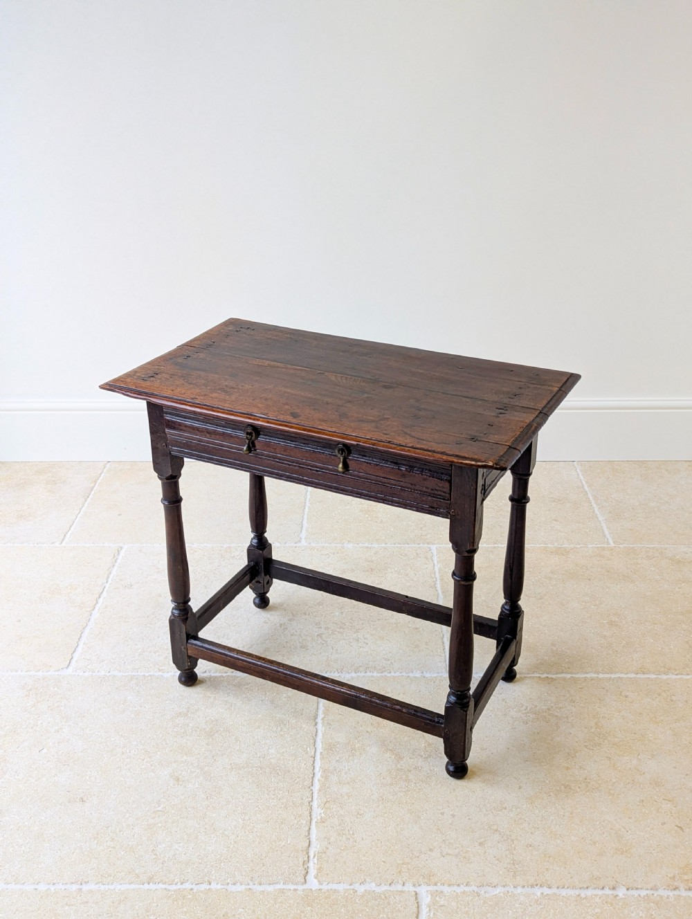 A late 17th-century dark oak side table with turned legs, lower stretchers, and a single drawer featuring brass drop handles. View VIII