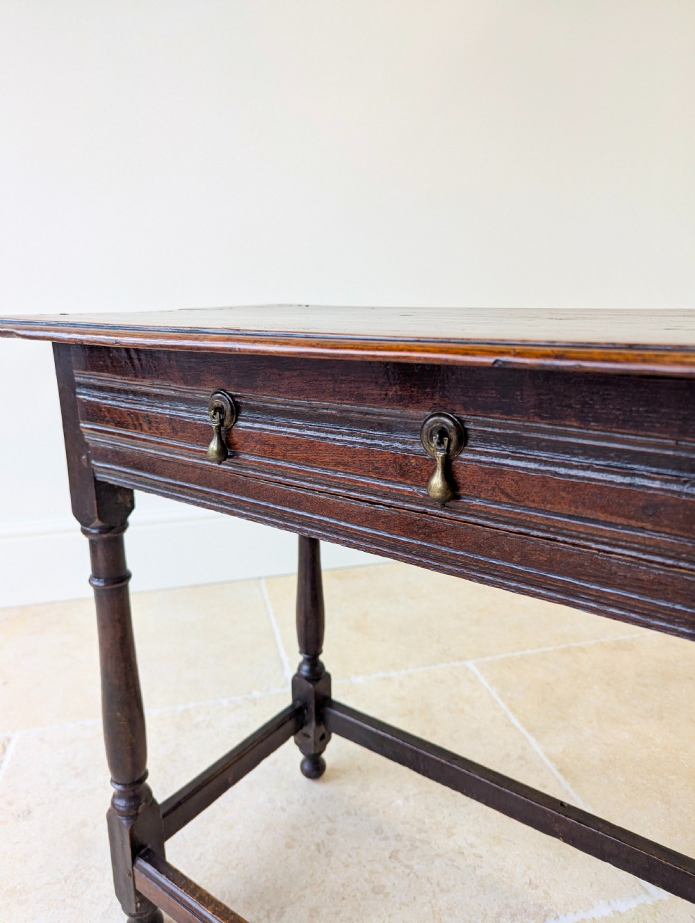 A late 17th-century dark oak side table with turned legs, lower stretchers, and a single drawer featuring brass drop handles. View IX