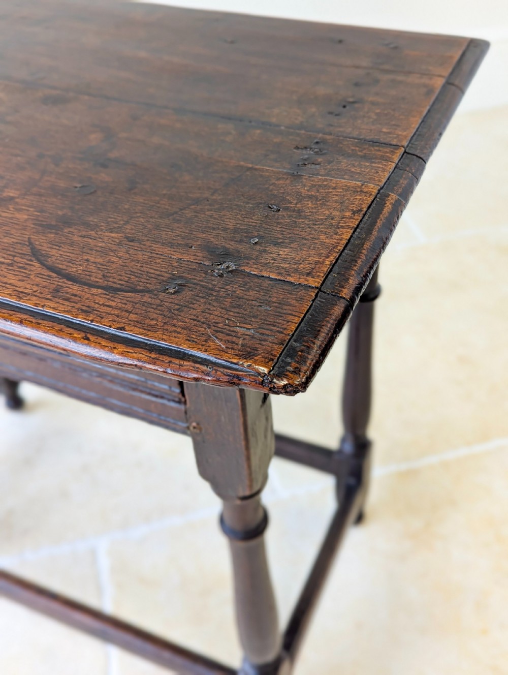 A late 17th-century dark oak side table with turned legs, lower stretchers, and a single drawer featuring brass drop handles. View XI