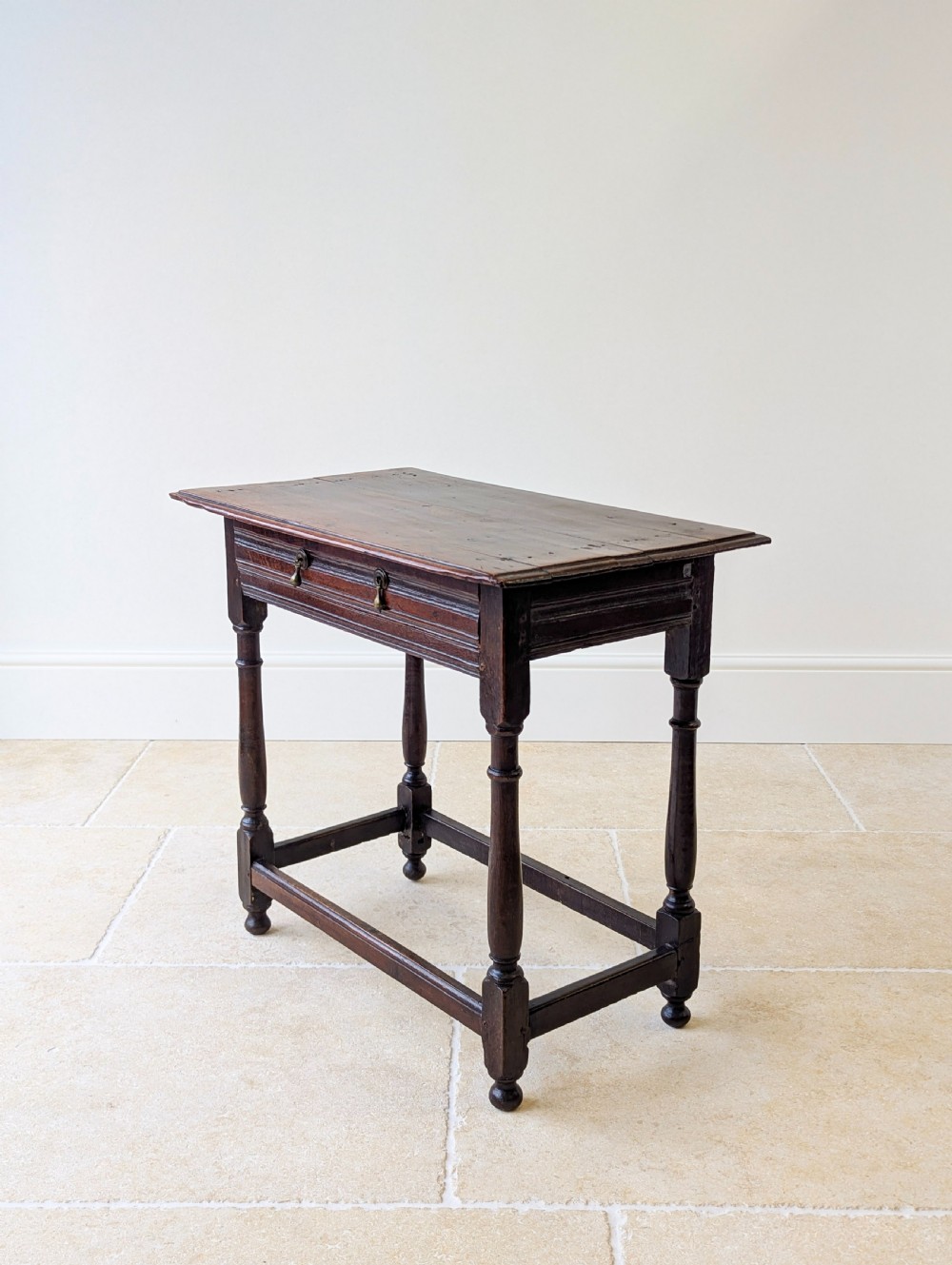 A late 17th-century dark oak side table with turned legs, lower stretchers, and a single drawer featuring brass drop handles. View XII