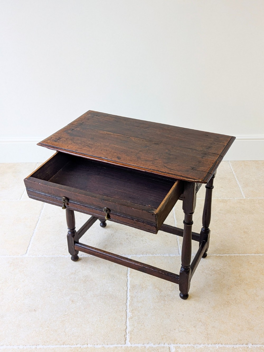 A late 17th-century dark oak side table with turned legs, lower stretchers, and a single drawer featuring brass drop handles. View XIV