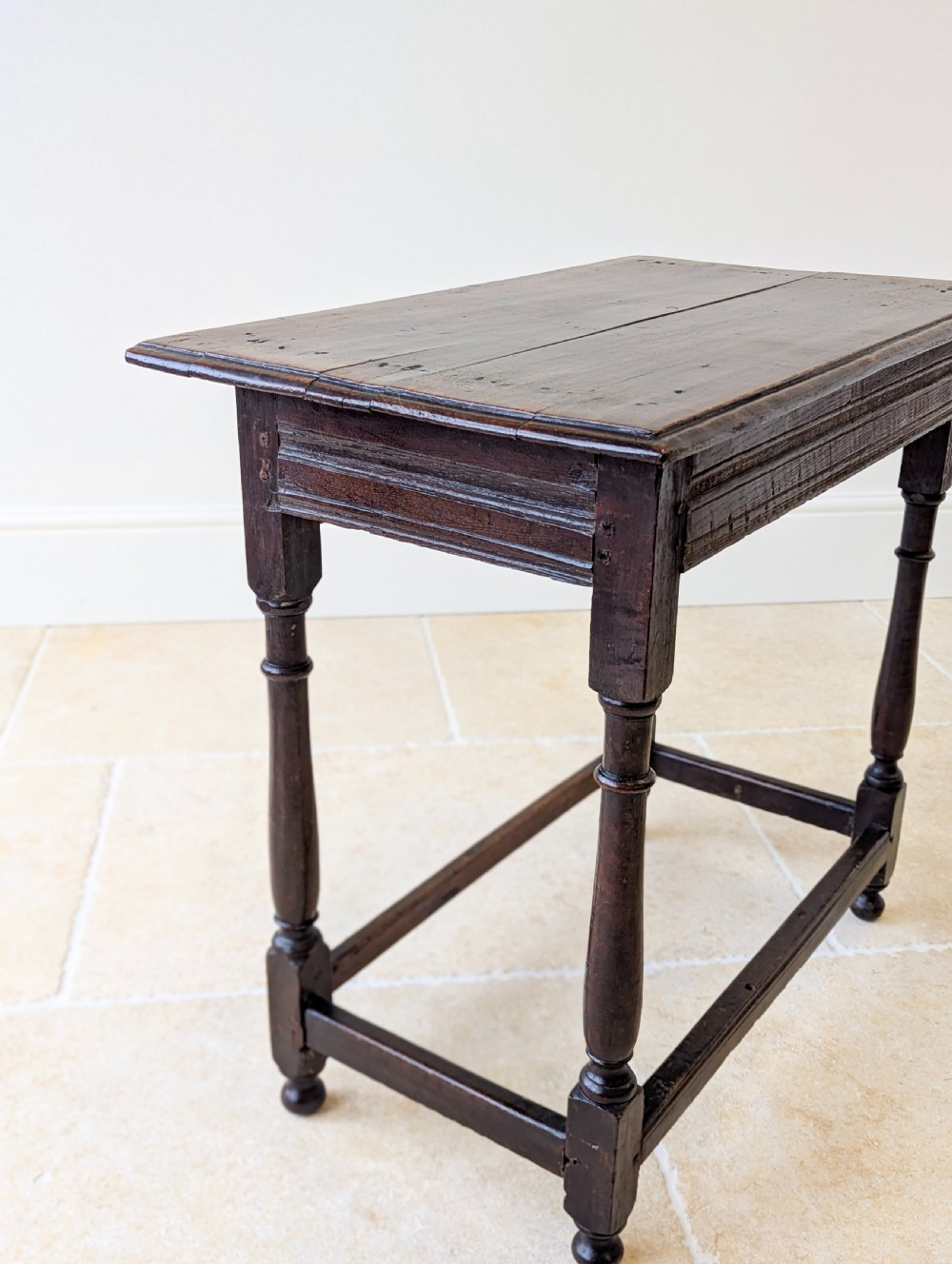 A late 17th-century dark oak side table with turned legs, lower stretchers, and a single drawer featuring brass drop handles. View XVII