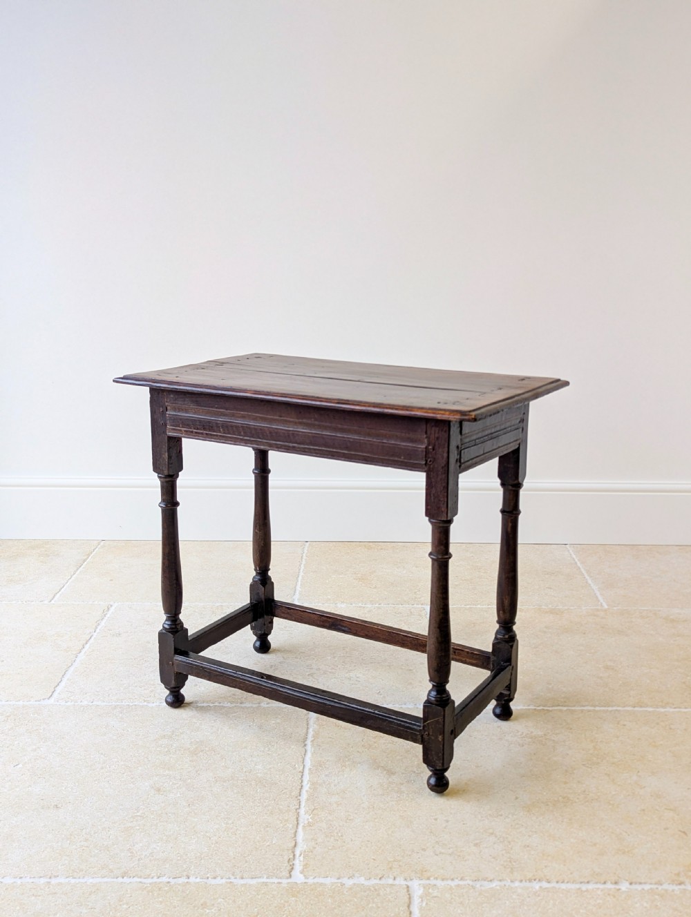 A late 17th-century dark oak side table with turned legs, lower stretchers, and a single drawer featuring brass drop handles. View XIX