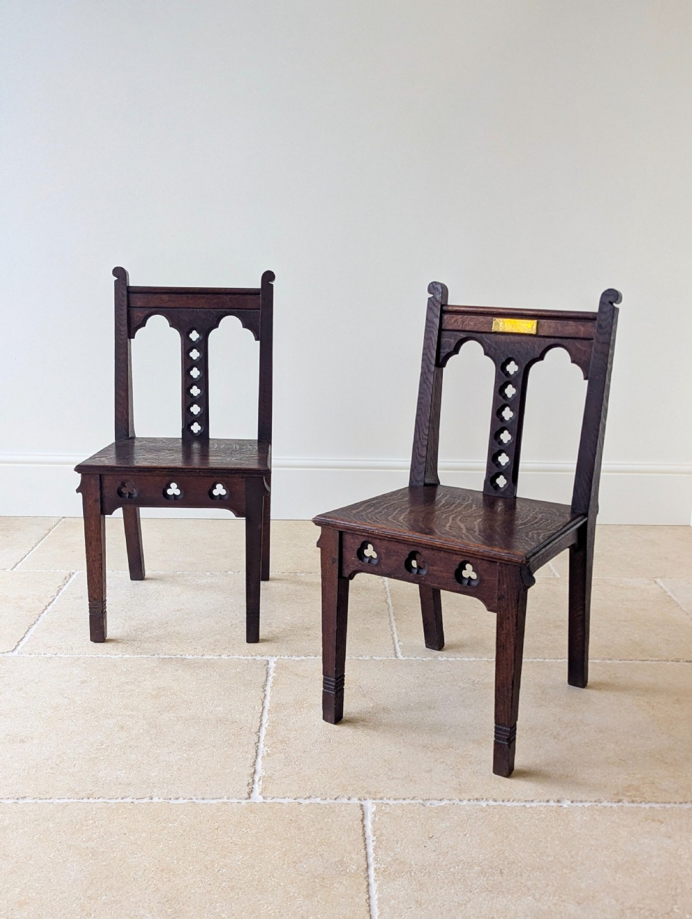 A pair of dark oak Edwardian Gothic Revival side chairs displaying trefoil cutouts, pointed arches, and solid square legs. View V