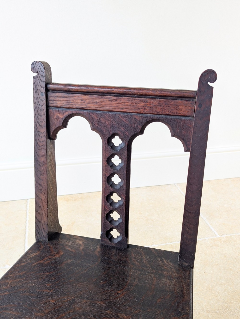A pair of dark oak Edwardian Gothic Revival side chairs displaying trefoil cutouts, pointed arches, and solid square legs. View IX