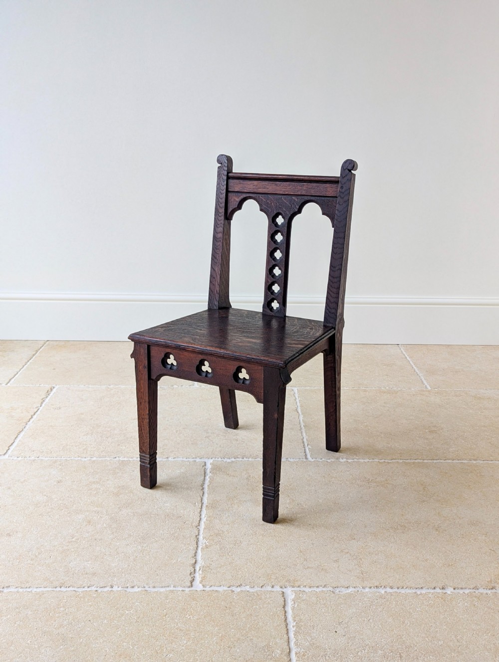 A pair of dark oak Edwardian Gothic Revival side chairs displaying trefoil cutouts, pointed arches, and solid square legs. View XIV