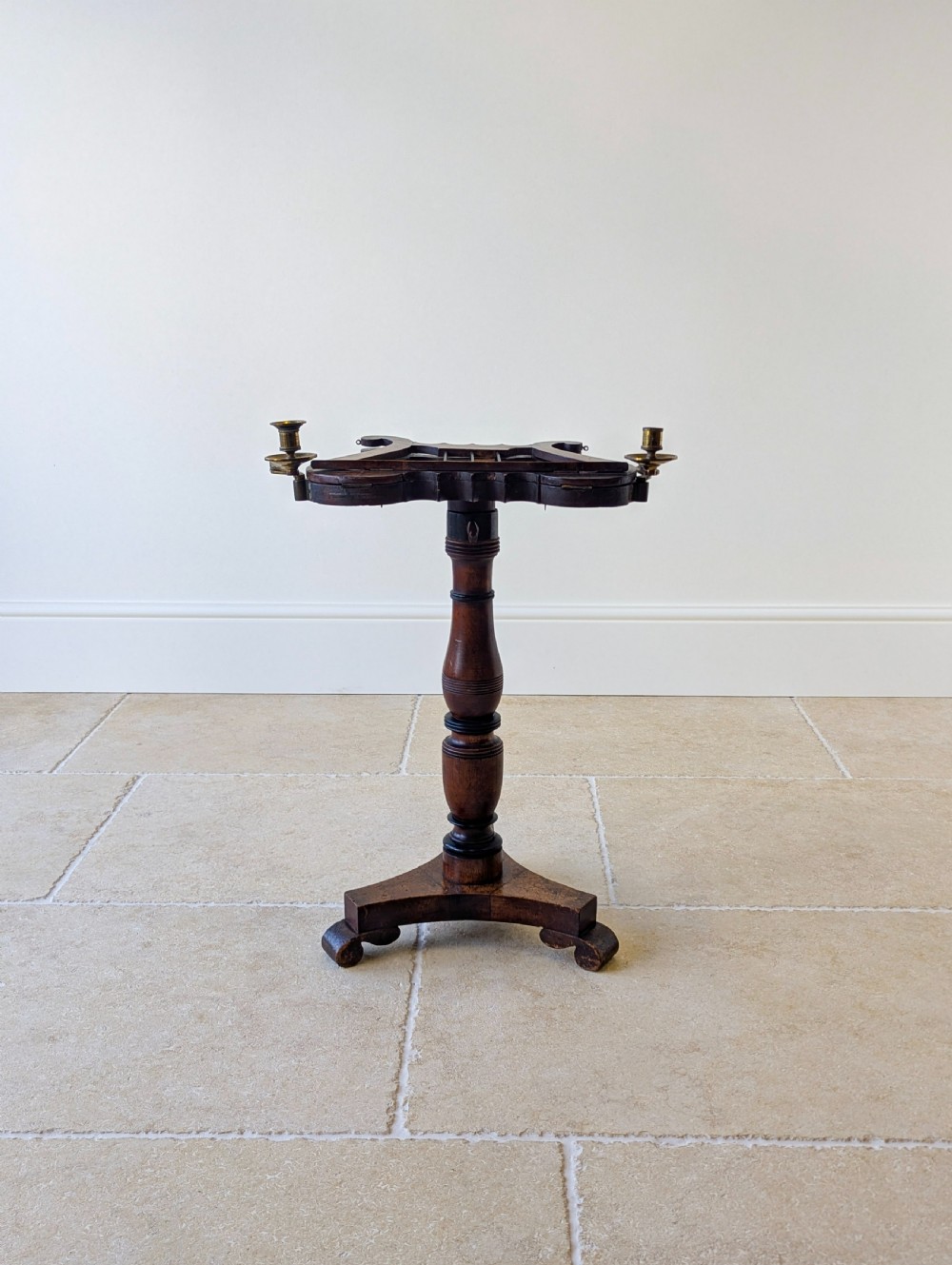 An antique mahogany music stand featuring a lyre-shaped sheet rest, dual brass candle sconces, a turned stem, and a carved tripod base. View V