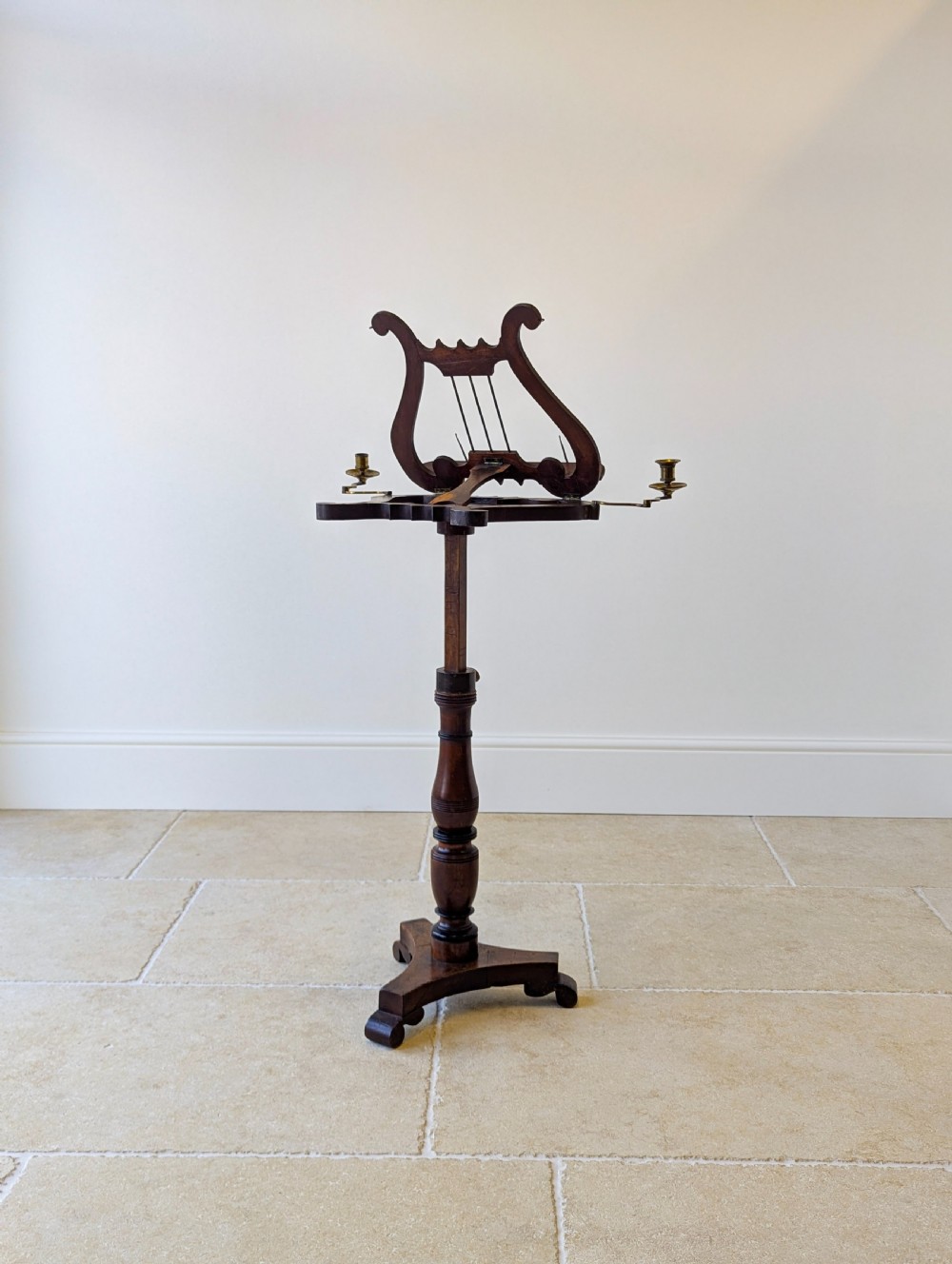 An antique mahogany music stand featuring a lyre-shaped sheet rest, dual brass candle sconces, a turned stem, and a carved tripod base. View VII