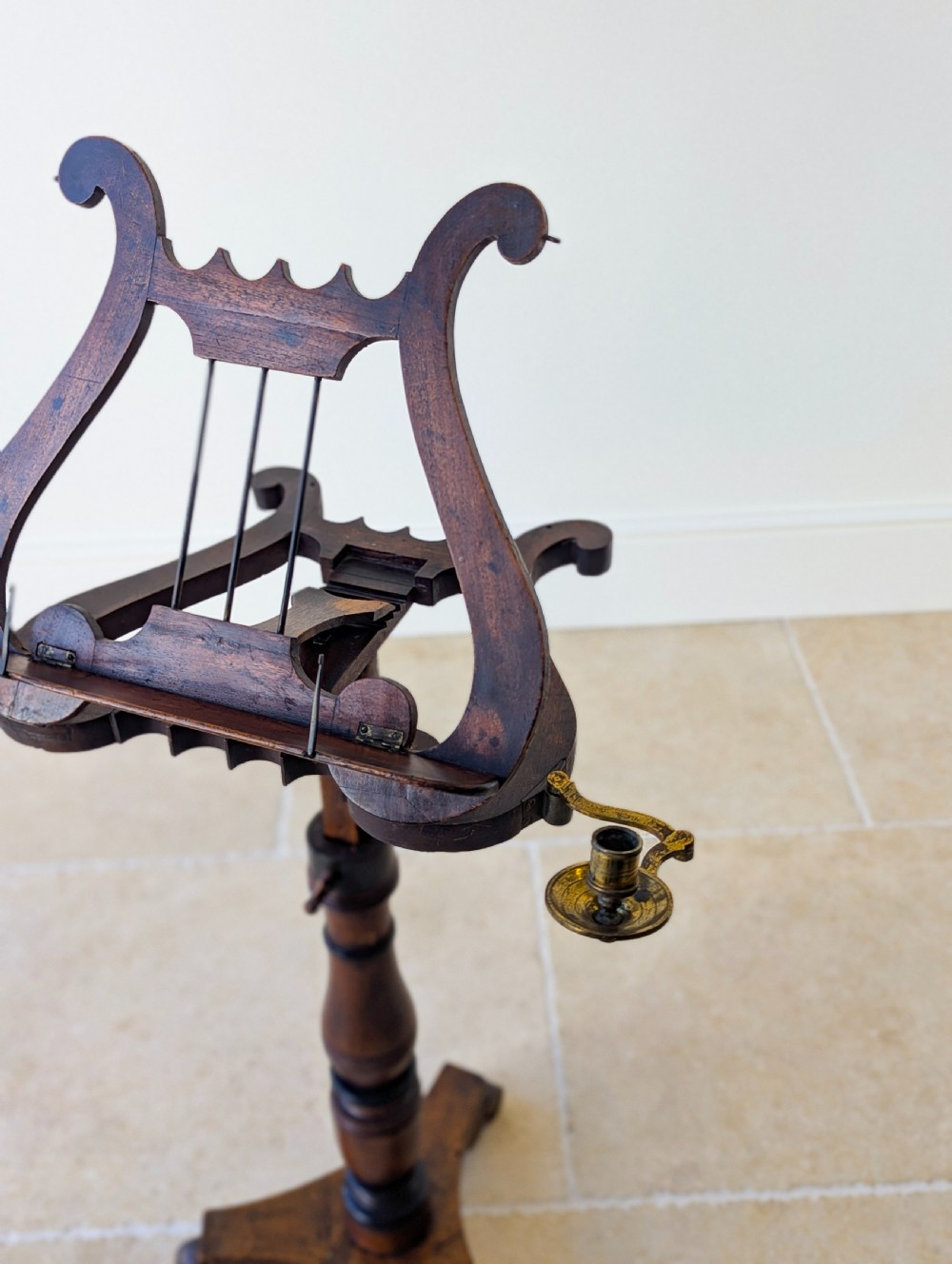 An antique mahogany music stand featuring a lyre-shaped sheet rest, dual brass candle sconces, a turned stem, and a carved tripod base. View IX