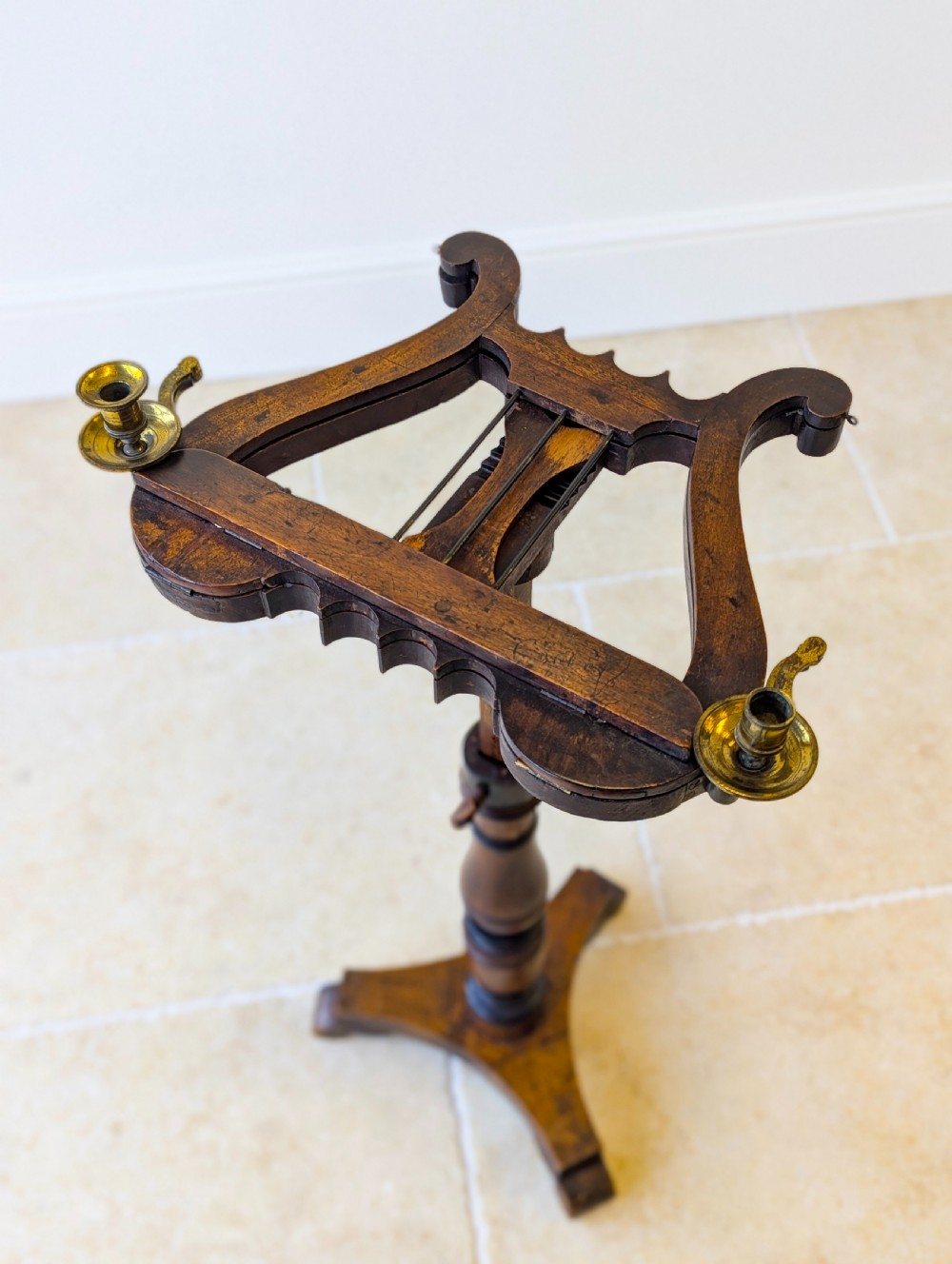 An antique mahogany music stand featuring a lyre-shaped sheet rest, dual brass candle sconces, a turned stem, and a carved tripod base. View XIV