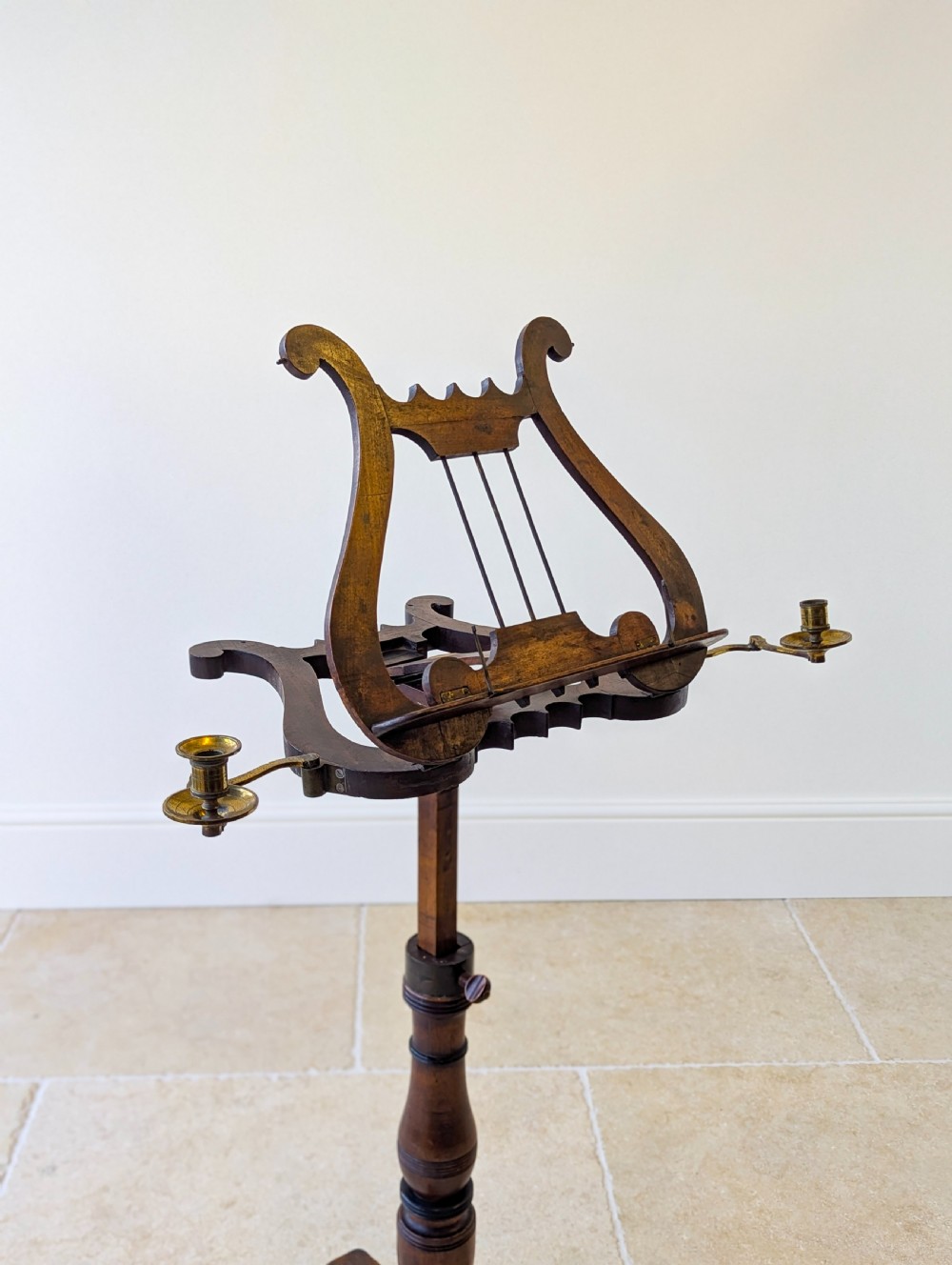 An antique mahogany music stand featuring a lyre-shaped sheet rest, dual brass candle sconces, a turned stem, and a carved tripod base. View XVI