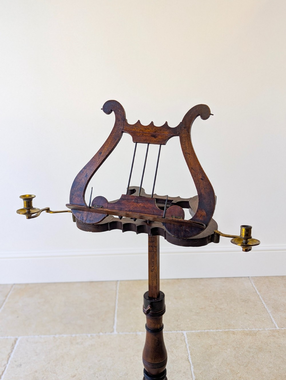 An antique mahogany music stand featuring a lyre-shaped sheet rest, dual brass candle sconces, a turned stem, and a carved tripod base. View XVIII