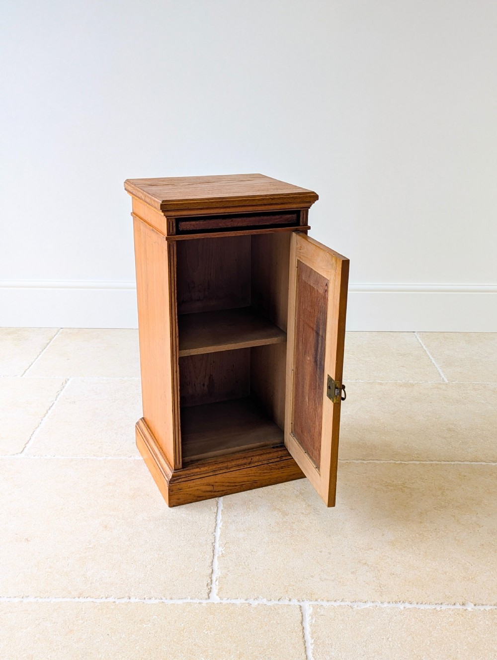 A late Victorian Aesthetic Movement oak bedside cabinet featuring an ebonised inset panel door and drop ring handle. View II