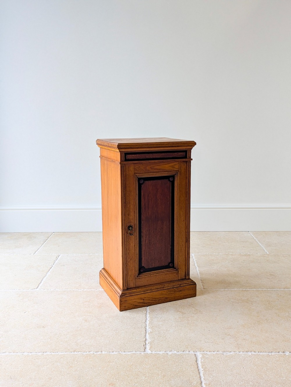 A late Victorian Aesthetic Movement oak bedside cabinet featuring an ebonised inset panel door and drop ring handle. View VII