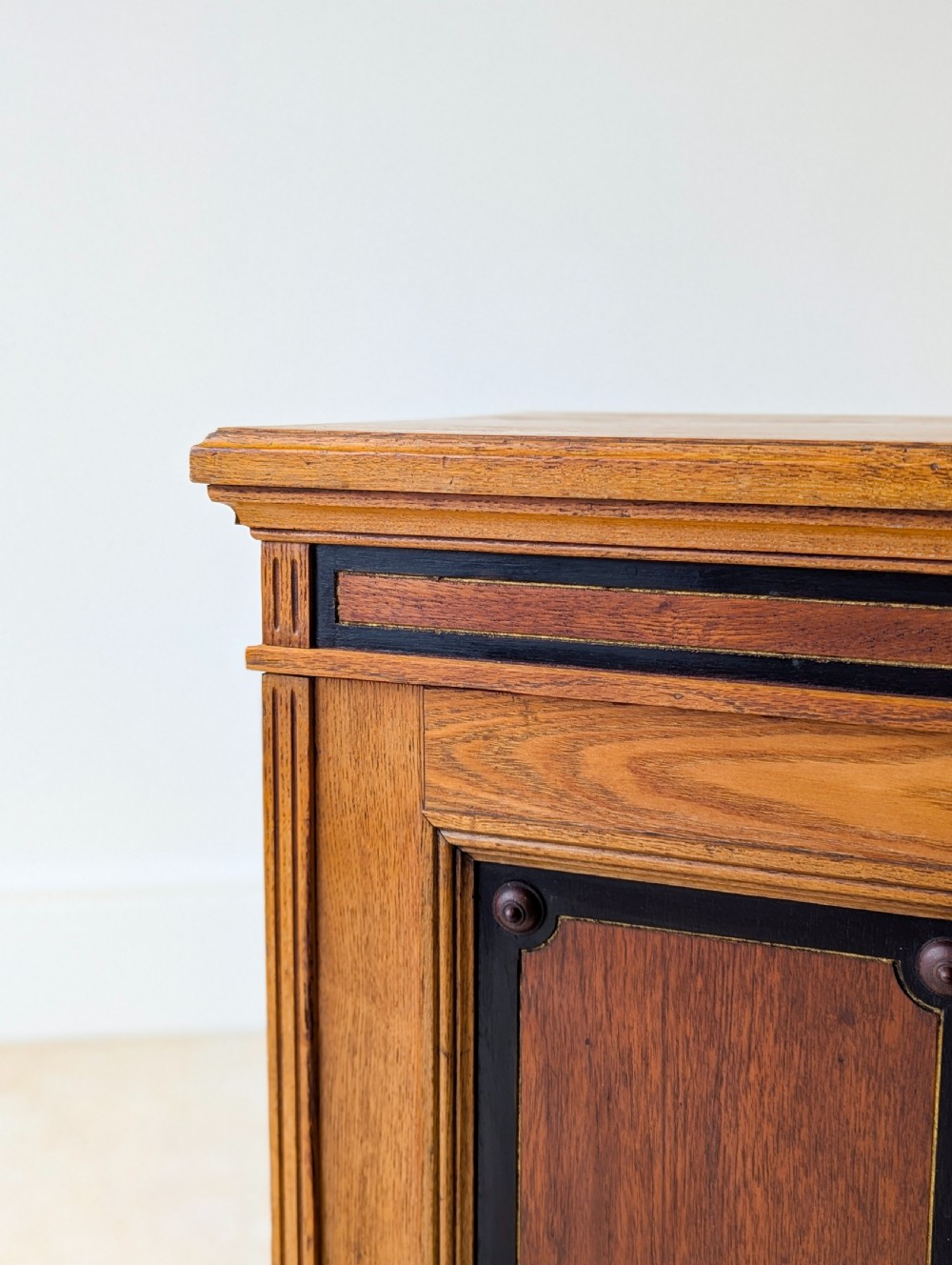 A late Victorian Aesthetic Movement oak bedside cabinet featuring an ebonised inset panel door and drop ring handle. View VIII