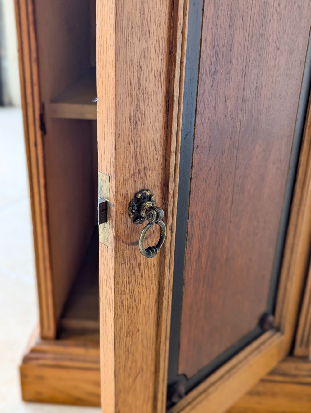 A late Victorian Aesthetic Movement oak bedside cabinet featuring an ebonised inset panel door and drop ring handle. View IX