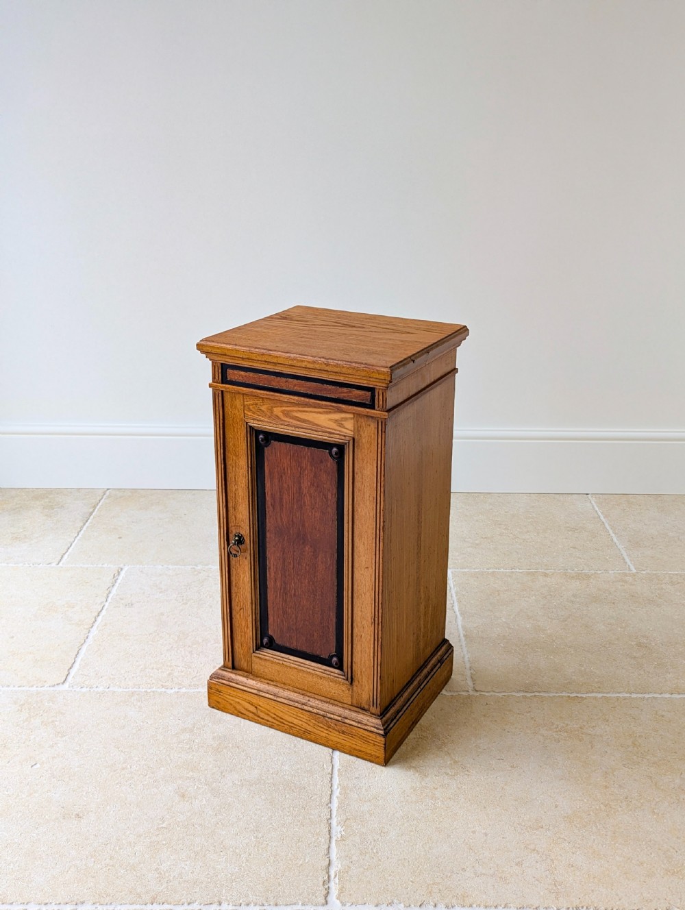 A late Victorian Aesthetic Movement oak bedside cabinet featuring an ebonised inset panel door and drop ring handle. View XI