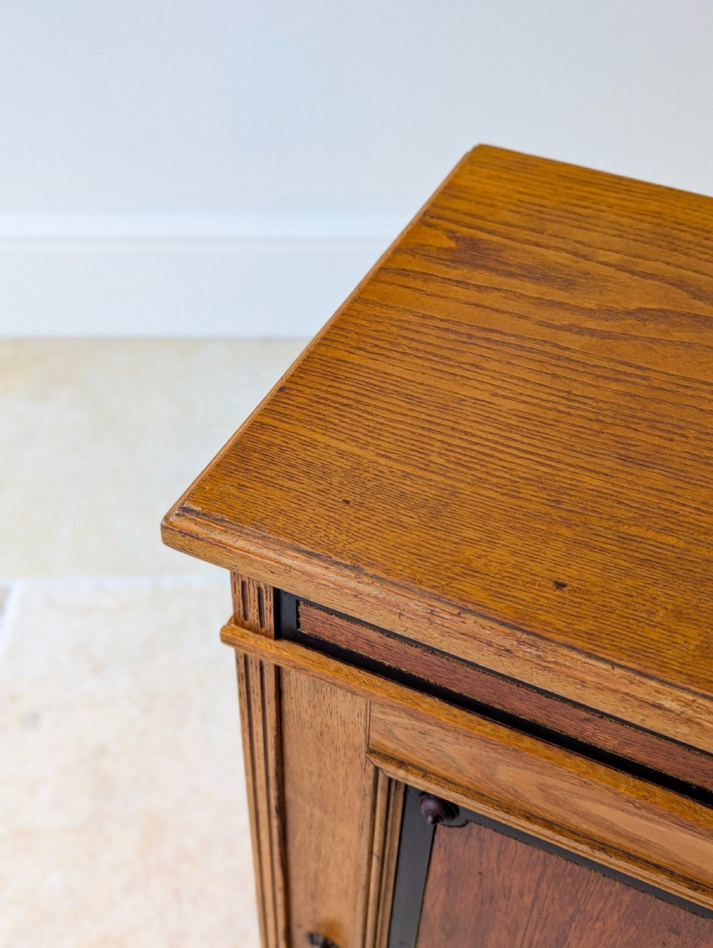 A late Victorian Aesthetic Movement oak bedside cabinet featuring an ebonised inset panel door and drop ring handle. View XII