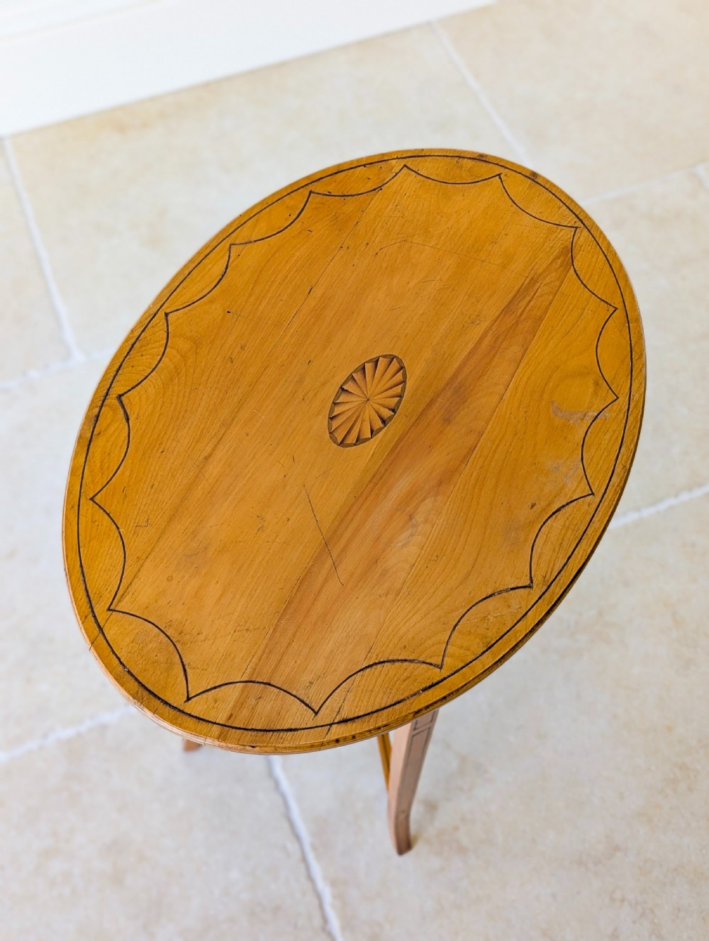 An Edwardian oval satinwood occasional table featuring delicate marquetry inlay on the top, slender splayed legs, and a small oval undertier. View III