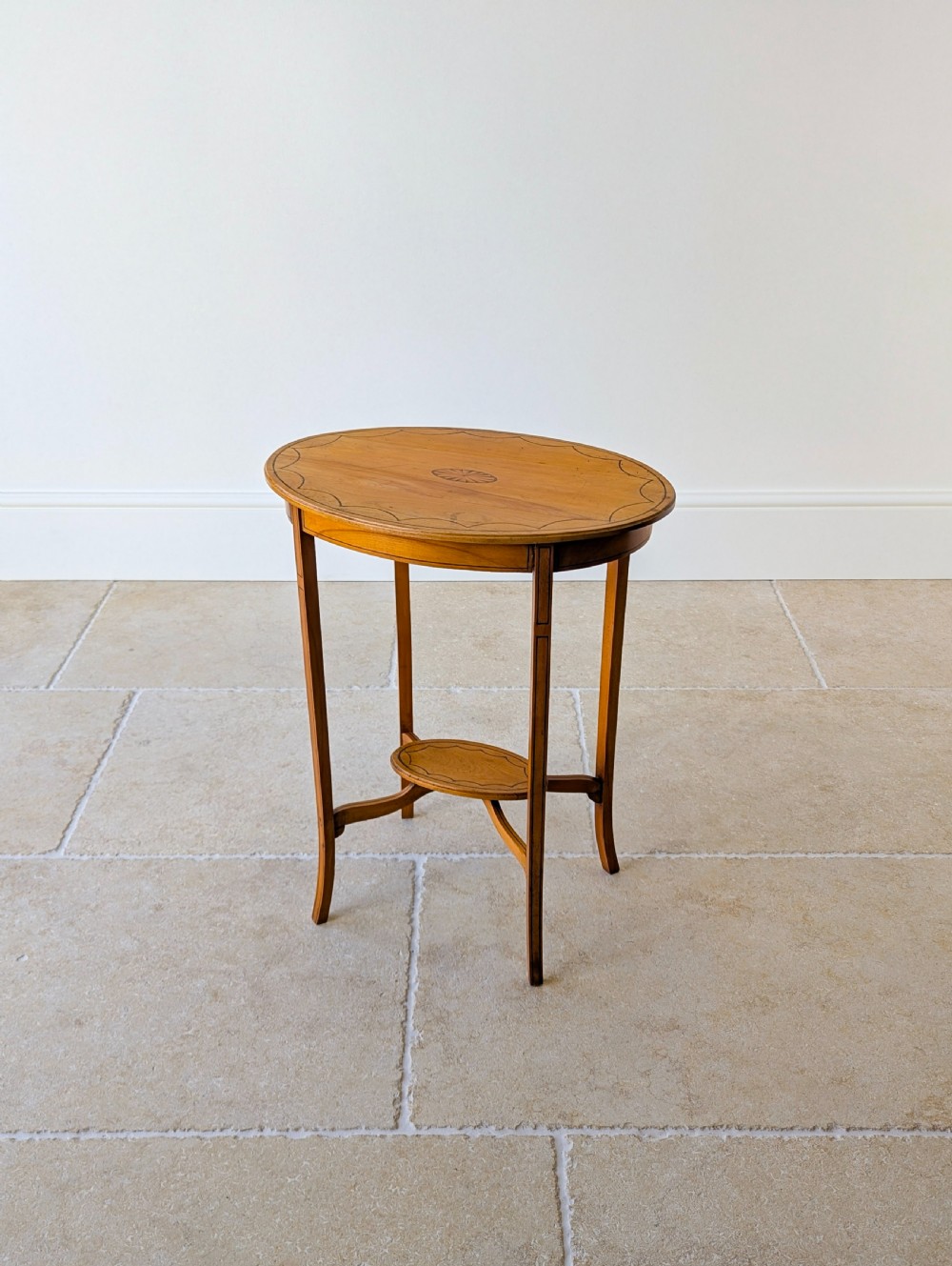 An Edwardian oval satinwood occasional table featuring delicate marquetry inlay on the top, slender splayed legs, and a small oval undertier. View VI