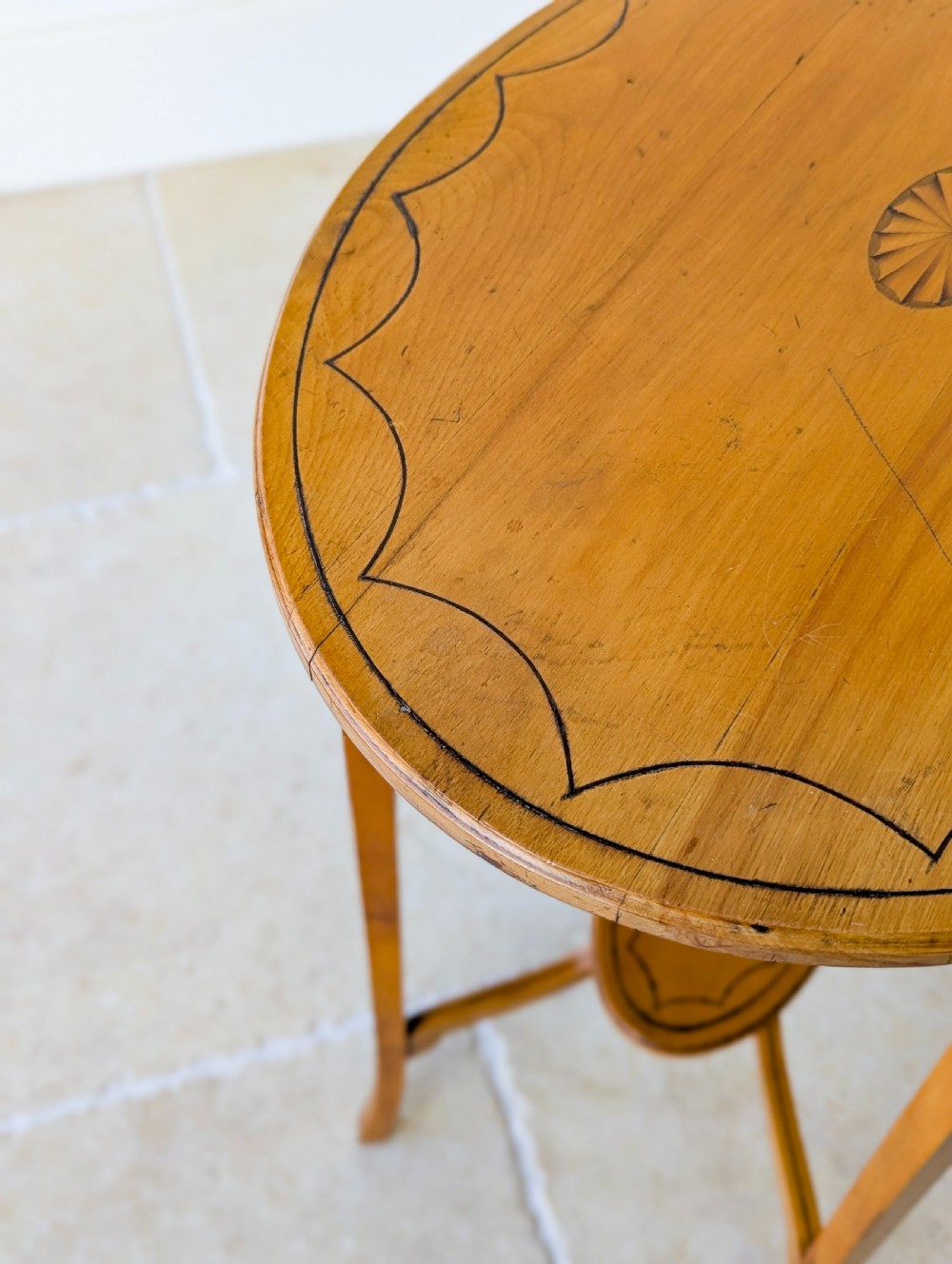 An Edwardian oval satinwood occasional table featuring delicate marquetry inlay on the top, slender splayed legs, and a small oval undertier. View IX