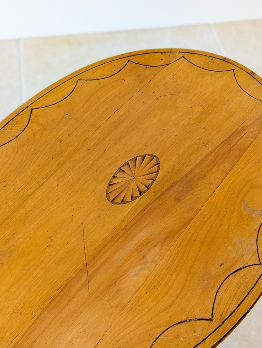 An Edwardian oval satinwood occasional table featuring delicate marquetry inlay on the top, slender splayed legs, and a small oval undertier. View X