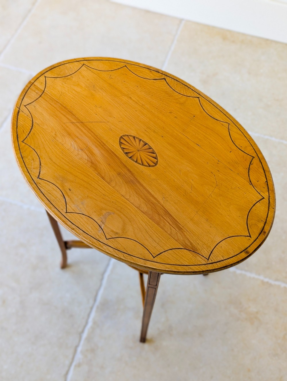 An Edwardian oval satinwood occasional table featuring delicate marquetry inlay on the top, slender splayed legs, and a small oval undertier. View XIII