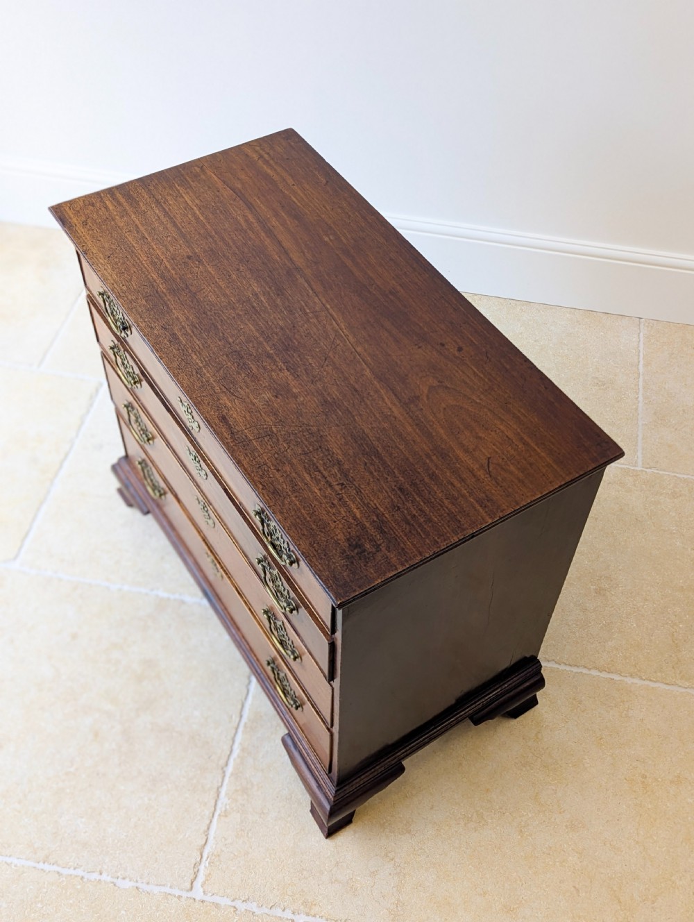 An antique George II mahogany chest of drawers featuring four graduated drawers with ornate brass handles on bracket feet. View III