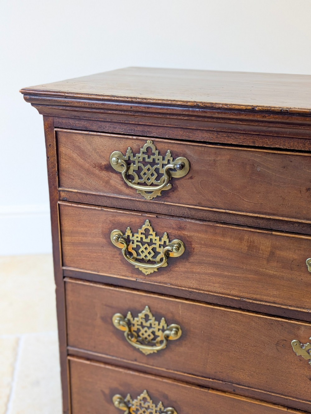 An antique George II mahogany chest of drawers featuring four graduated drawers with ornate brass handles on bracket feet. View VI