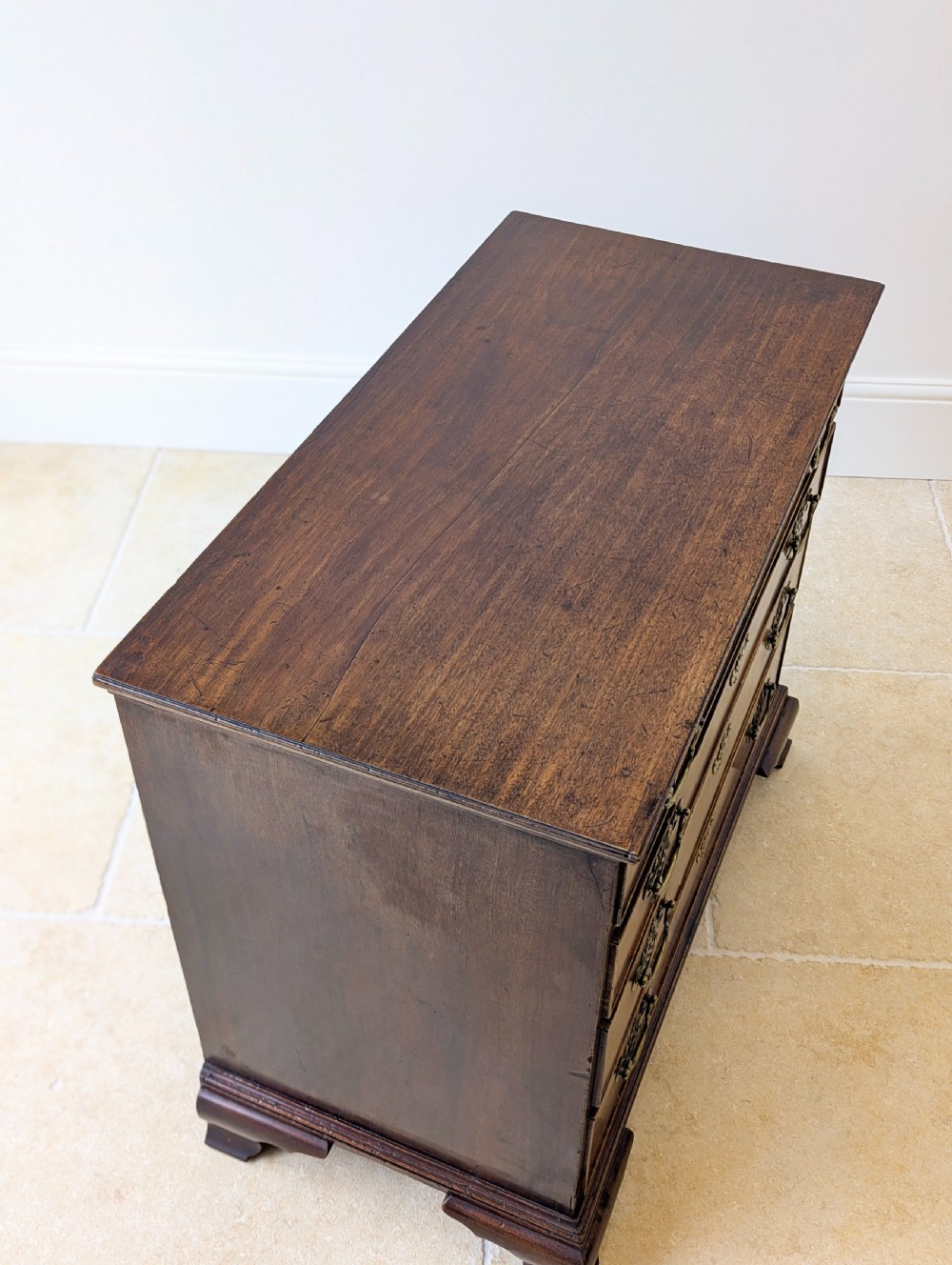 An antique George II mahogany chest of drawers featuring four graduated drawers with ornate brass handles on bracket feet. View VII