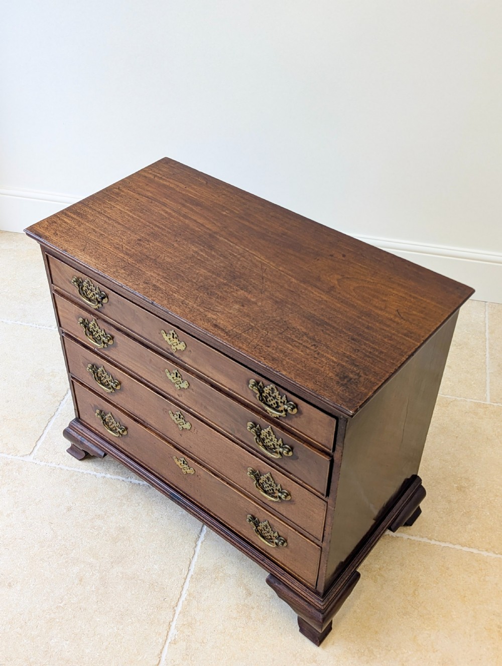 An antique George II mahogany chest of drawers featuring four graduated drawers with ornate brass handles on bracket feet. View VIII