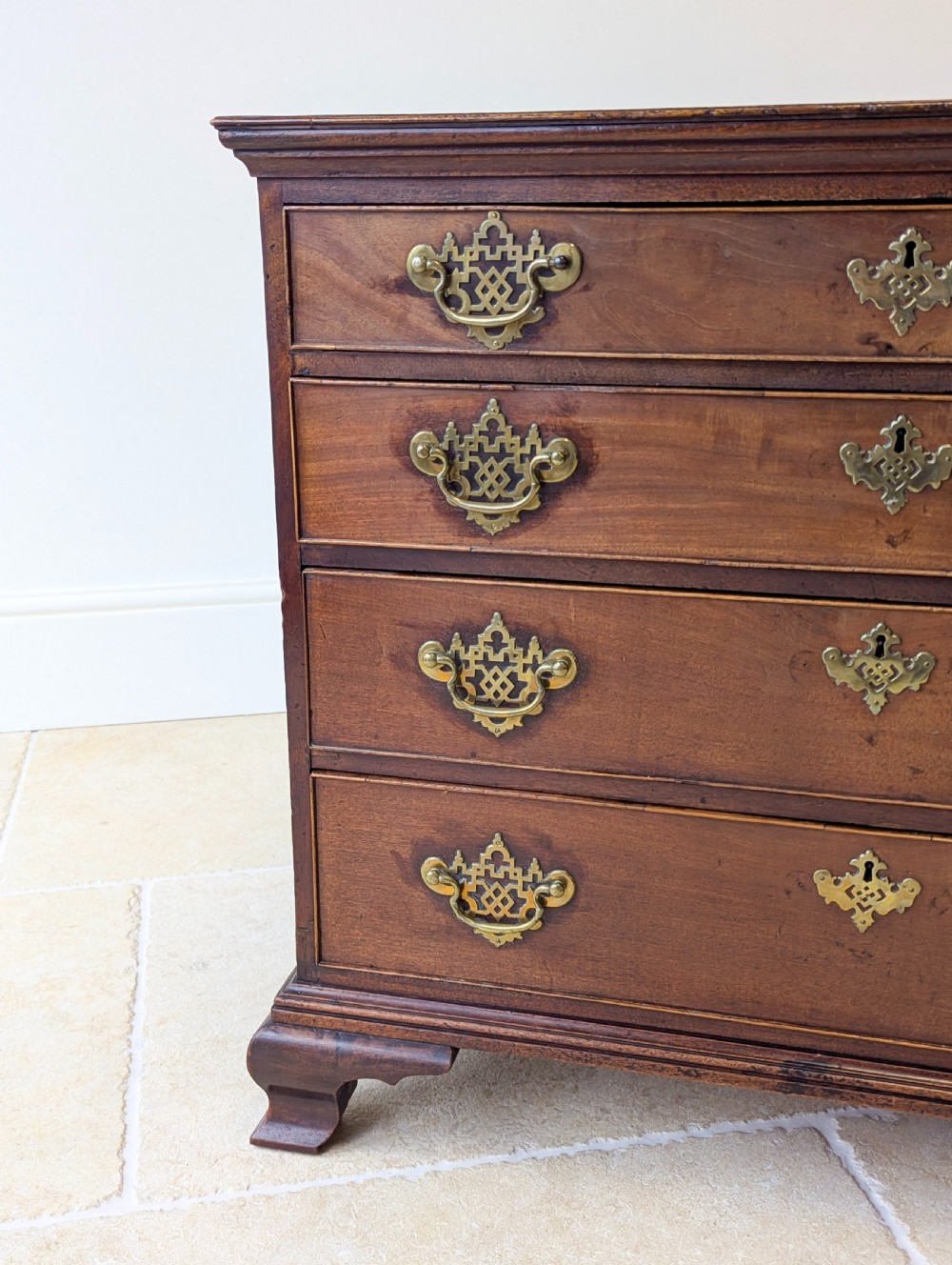 An antique George II mahogany chest of drawers featuring four graduated drawers with ornate brass handles on bracket feet. View IX