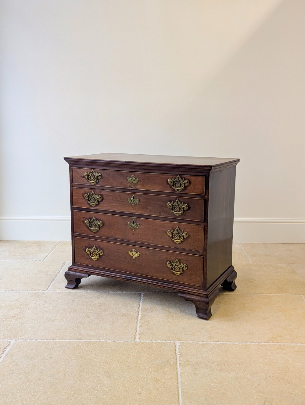 An antique George II mahogany chest of drawers featuring four graduated drawers with ornate brass handles on bracket feet. View XI