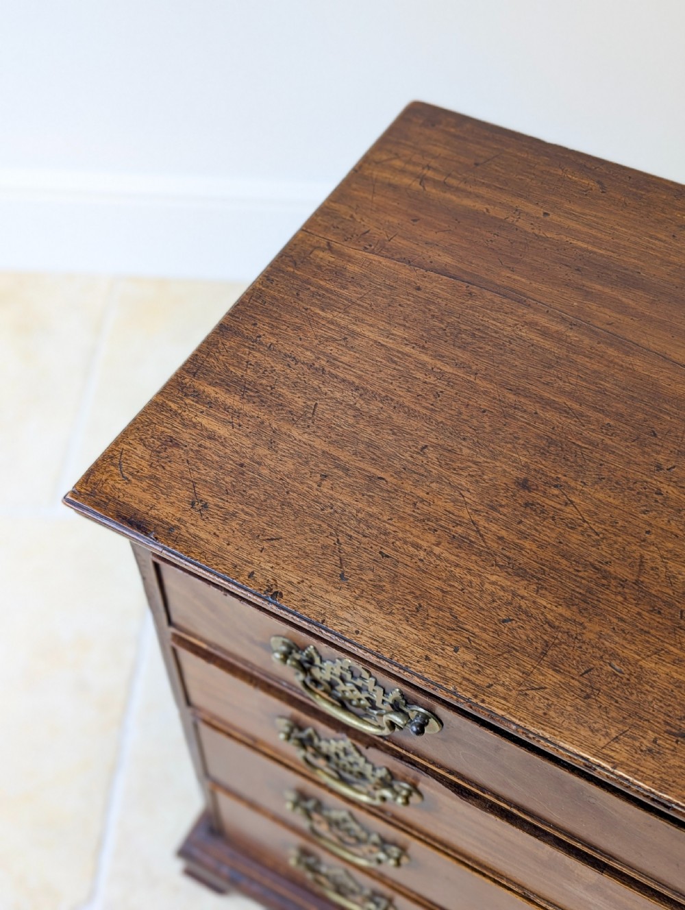 An antique George II mahogany chest of drawers featuring four graduated drawers with ornate brass handles on bracket feet. View XII