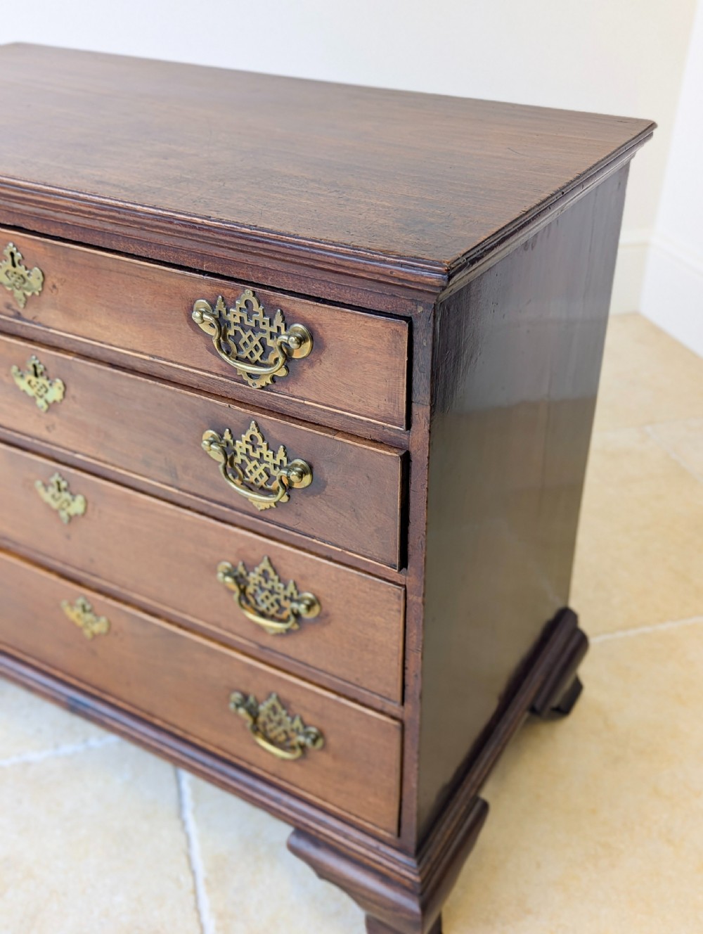 An antique George II mahogany chest of drawers featuring four graduated drawers with ornate brass handles on bracket feet. View XIII