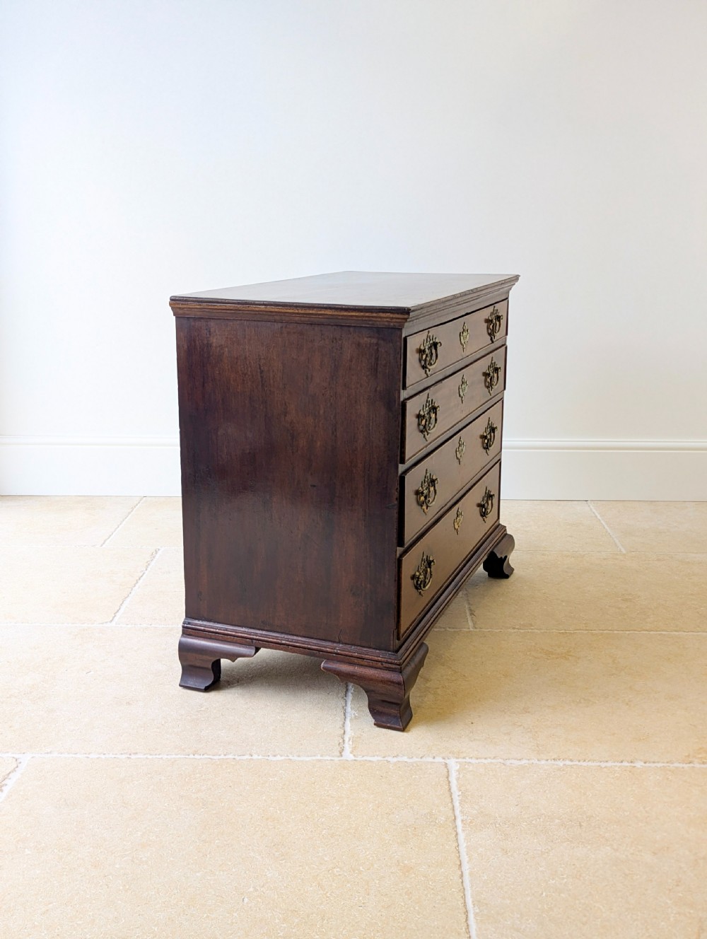 An antique George II mahogany chest of drawers featuring four graduated drawers with ornate brass handles on bracket feet. View XIV