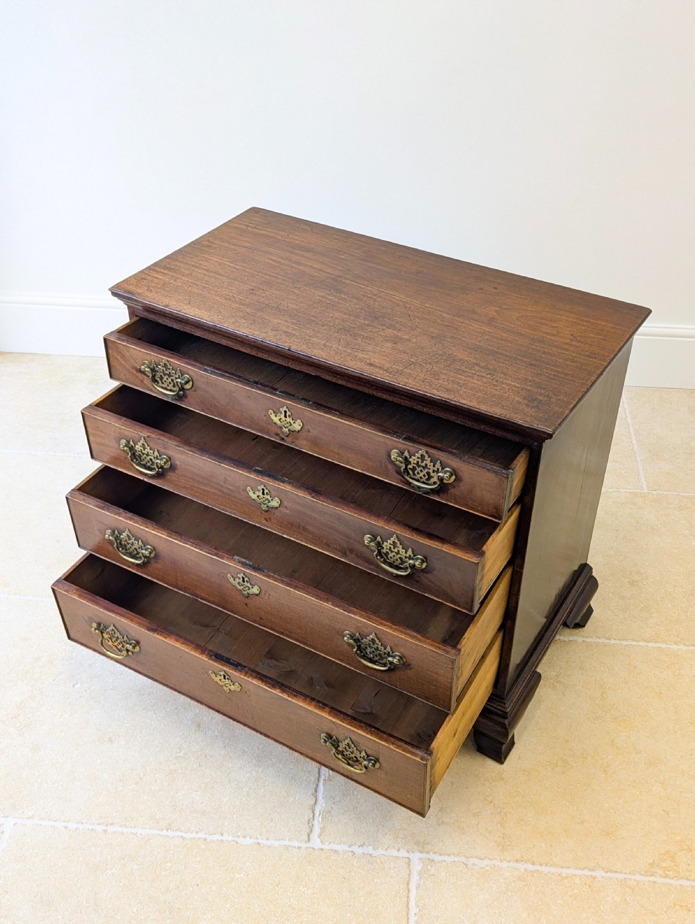 An antique George II mahogany chest of drawers featuring four graduated drawers with ornate brass handles on bracket feet. View XV