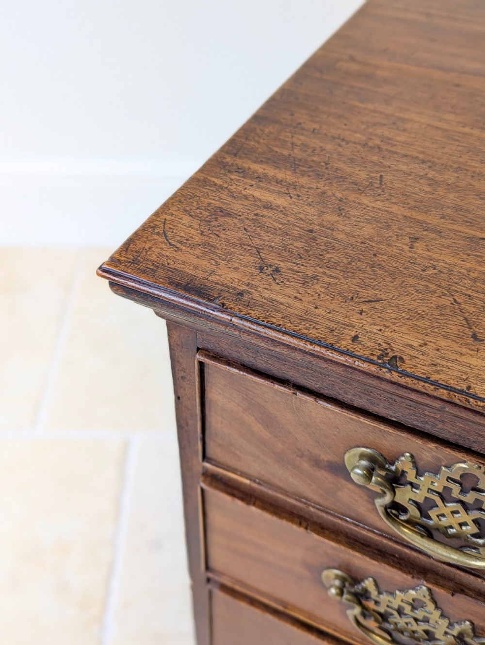 An antique George II mahogany chest of drawers featuring four graduated drawers with ornate brass handles on bracket feet. View XVI