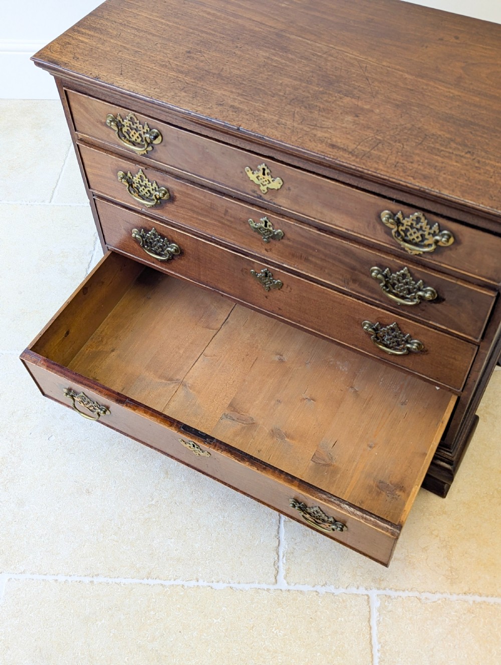 An antique George II mahogany chest of drawers featuring four graduated drawers with ornate brass handles on bracket feet. View XVII