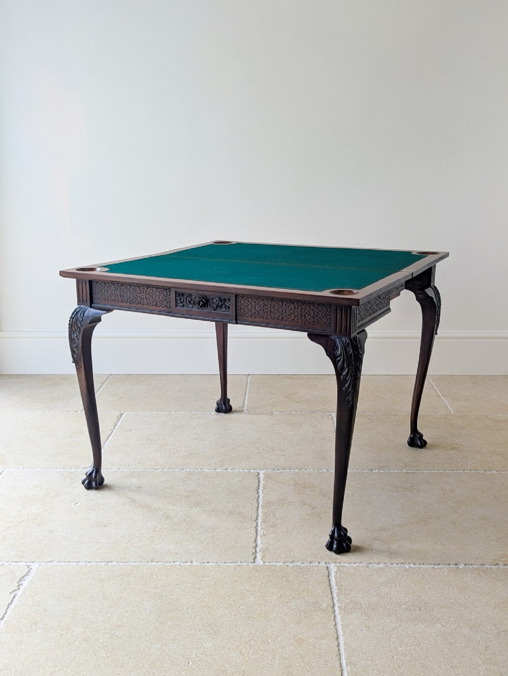 A square Victorian dark mahogany card table with a green baize playing surface, carved cabriole legs, ball-and-claw feet, and corner counter wells.